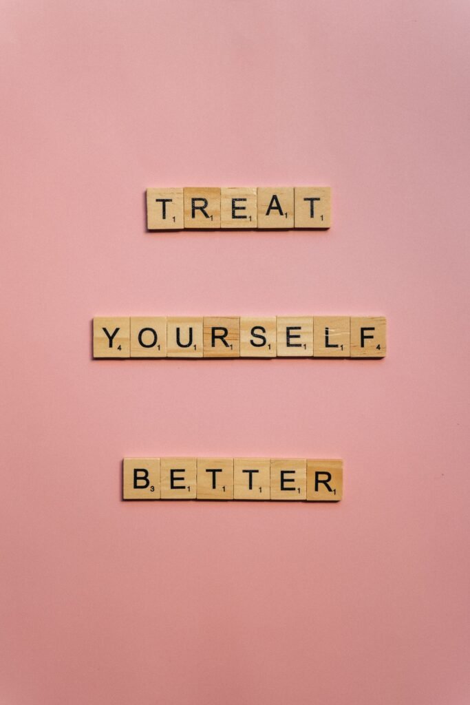Scrabble tiles spelling 'Treat Yourself Better' on a pink background.