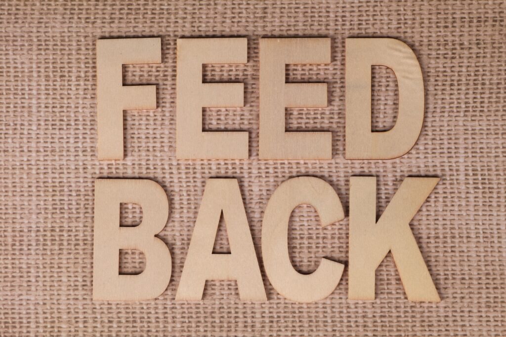 Wooden letters spelling 'FEEDBACK' on a burlap background, emphasizing communication.